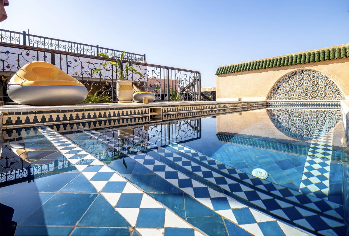 Piscina de zellige azul y blanco en la azotea del Riad Hamdane, tejas verdes de Fez al fondo